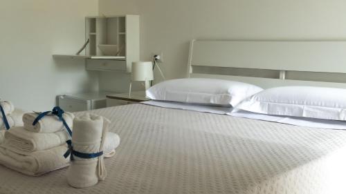 a bedroom with a bed with white pillows and towels at Pepi B&B in Santa Maria di Castellabate