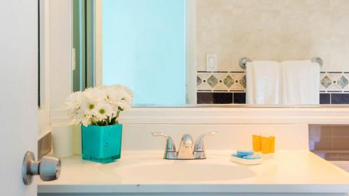 a bathroom sink with a vase of flowers and a mirror at New Point Miami Beach Apartments in Miami Beach