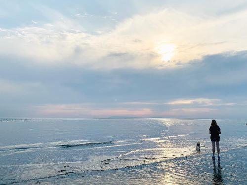 a woman standing on the beach with a dog at The Hideout in Chichester