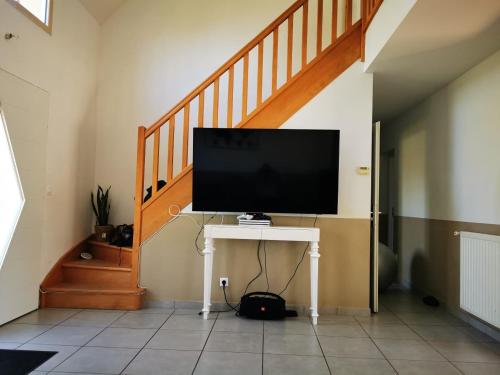 einen TV auf einem Tisch in einem Zimmer mit einer Treppe in der Unterkunft VENT DE FOLIE in Le Crotoy