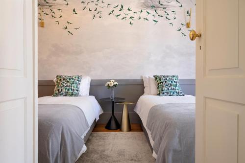 twee bedden in een kamer met vogels aan de muur bij Historic apartment at Cardosas with balcony in Porto