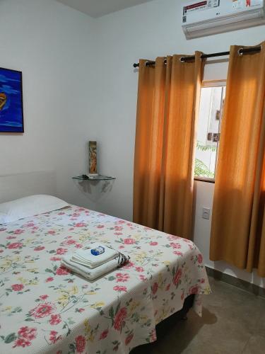 a bedroom with a bed and a window with orange curtains at Suite 03 - Independente, privativa e aconchegante in Cuiabá