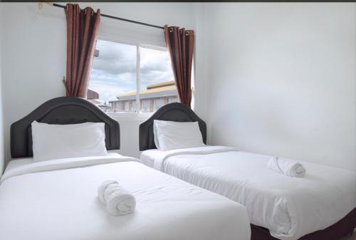 two twin beds in a room with a window at Mee Hug Guesthouse in Phayao