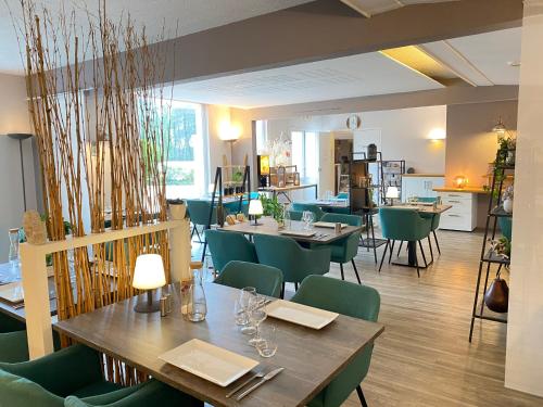 a dining room with tables and green chairs at Logis Latitude Ouest Hôtel Restaurant & Spa in Locronan
