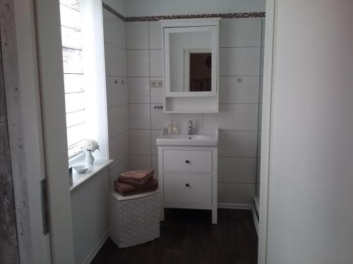 Baño blanco con lavabo y espejo en Fischerhaus König in Alt Sassnitz, en Sassnitz