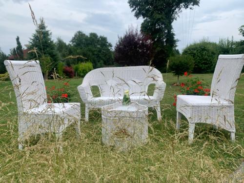three white chairs and a table in a field at Agro na Wapniarni in Białla