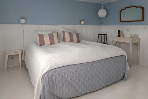 a bedroom with a large white bed with pillows at Egn Boutique Hotel in Stege