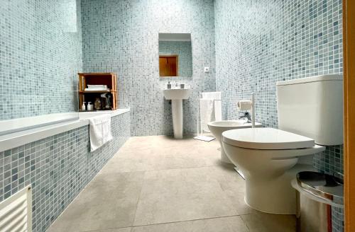 uma casa de banho com WC, lavatório e azulejos azuis em Solar Pontes em Capelas