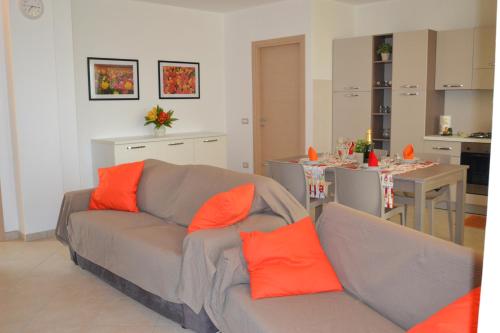 ein Wohnzimmer mit einem grauen Sofa und orangefarbenen Kissen in der Unterkunft Casa di Gian in Arnasco