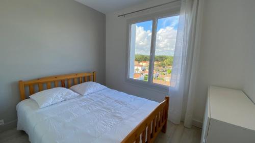 a white bedroom with a bed and a window at Appartement 3 chambres, panoramique vue océan in Saint-Jean-de-Monts