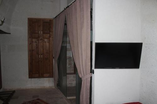 a window with a curtain and a television on a wall at Kemerli House in Avanos