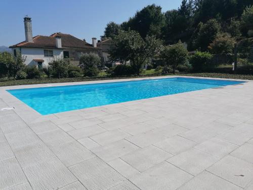 una piscina de agua azul frente a una casa en Quinta Vale do Nox, en Serrazes