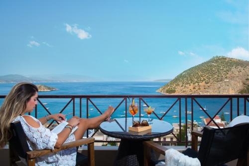 a woman sitting at a table on a balcony overlooking the ocean at King Minos Hotel in Tolo
