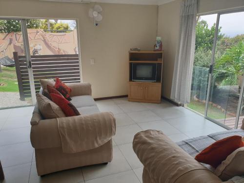 a living room with two couches and a tv at Amakaya Backpackers Travellers Accommodation in Plettenberg Bay