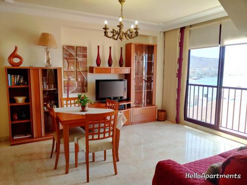 een woonkamer met een tafel en een televisie bij Sun Terrace Los Cristianos by HelloApartments in Los Cristianos