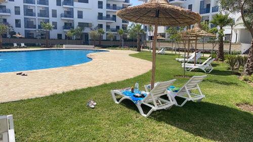 due sedie e un ombrellone accanto alla piscina di Appartement de luxe avec piscine a 5 min de la plage a Martil