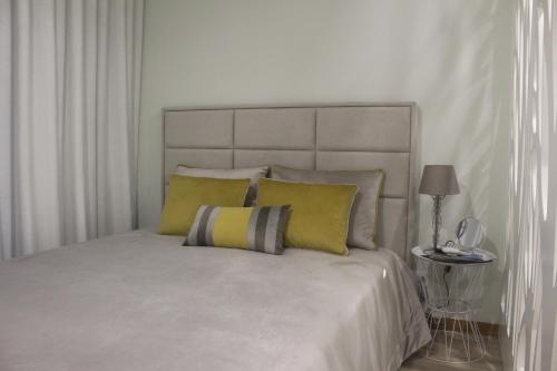 um quarto com uma cama grande e almofadas amarelas em Praia Horizonte Studio's - RRAL nº3195 em Praia da Vitória