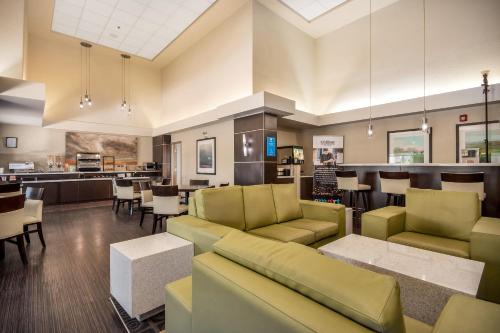 a living room with a couch and chairs and a bar at Home Inn & Suites Regina East in Regina
