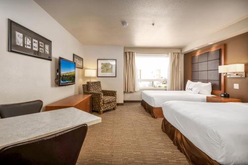 a hotel room with two beds and a chair at Home Inn & Suites Regina East in Regina