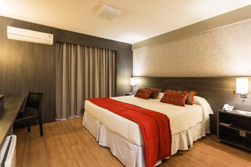 a hotel room with a bed and a desk at Faial Prime Suítes in Florianópolis