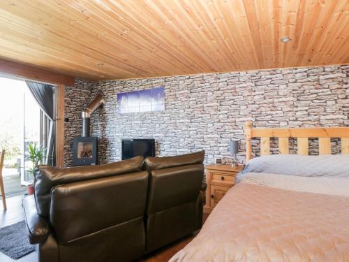 a bedroom with a bed and a brick wall at Blackbrae Cabin in Coatbridge