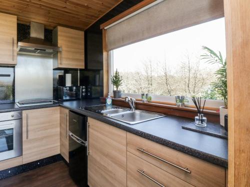 a kitchen with a sink and a large window at Blackbrae Cabin in Coatbridge