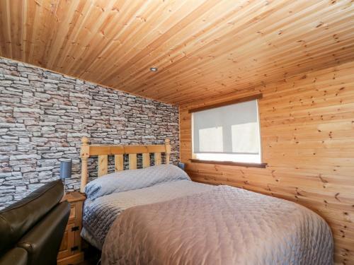 a bedroom with a bed and a brick wall at Blackbrae Cabin in Coatbridge