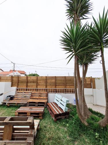 a patio with benches and palm trees in a yard at Cloud to Chill Surfhouse Baleal in Ferrel