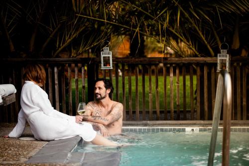 un hombre y una mujer sentados en una piscina con una copa de vino en boon hotel + spa - adults only, en Guerneville