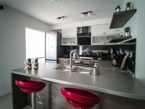a kitchen with red bar stools and a sink at Holiday Home Tos in Risika