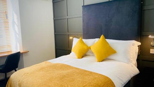 a bedroom with a bed with two yellow pillows at Siberia Bar & Hotel in Aberdeen