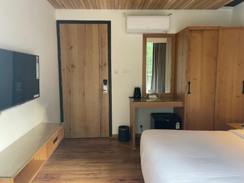 a bedroom with a bed and a flat screen tv at Moksha Riverside Resort in Kasol