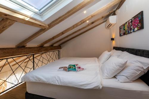 Un dormitorio con una cama blanca con un libro. en GAMA Dubrovnik, en Dubrovnik