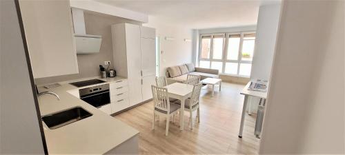 a kitchen with white cabinets and a table and chairs at Cozy White Home in Getxo in Getxo