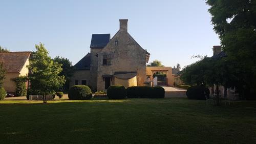 une grande maison en pierre avec une cour herbeuse dans l'établissement Manoir de la Croix Verte, à Le Bailleul