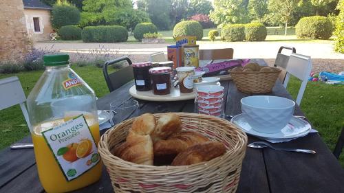 - une table de pique-nique avec un panier de pain et une bouteille de jus d'orange dans l'établissement Manoir de la Croix Verte, à Le Bailleul