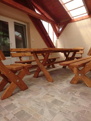 a wooden picnic table and benches in a building at Bé-La 2 Vendégház in Szomolya