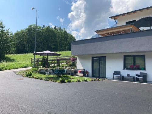 a house with a patio with an umbrella and chairs at Haus Bazigg in Klösterle am Arlberg