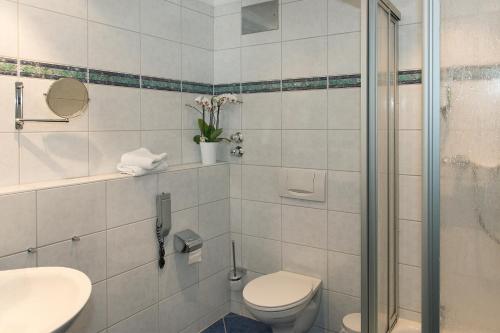 a white bathroom with a toilet and a shower at Hotel Restaurant Zum Schiffchen in Maintal