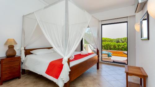 Schlafzimmer mit Himmelbett und Balkon in der Unterkunft Victory Village Quinta do Lago - Spacious 2 Bed / 3 Bath Apartment in Almancil
