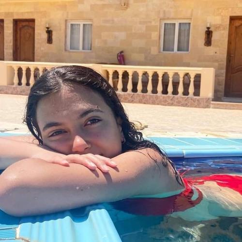 a young girl laying in a swimming pool at Ciao Hotel in Nuweiba