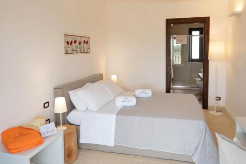 a white bedroom with a bed and a bathroom at TERRA TERRA - Masseria Minunni in Conversano