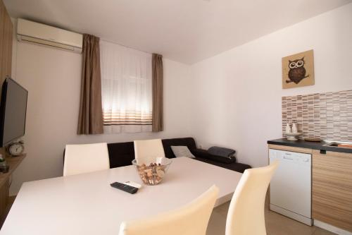 a kitchen with a white table and white chairs at Apartmani Olivia in Bibinje