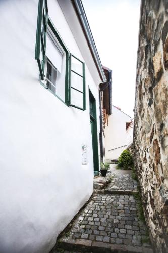 an alley between two white buildings with green windows at Domeček / Tiny House in Český Krumlov