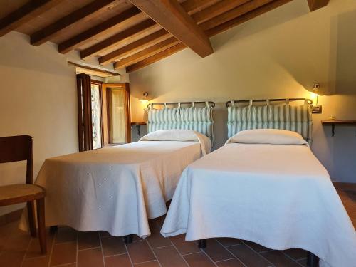 two beds with white linens in a room at Agriturismo Cardella in Piobbico