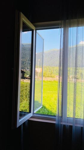 a window with a view of a green field at Lela Guest House in Mestia