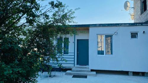 a white house with a blue door and stairs at Lela Guest House in Mestia