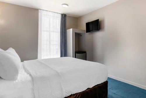 a bedroom with a white bed and a television at Econo Lodge in Montréal