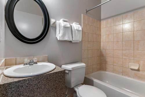 y baño con lavabo, aseo y espejo. en Econo Lodge, en Montreal