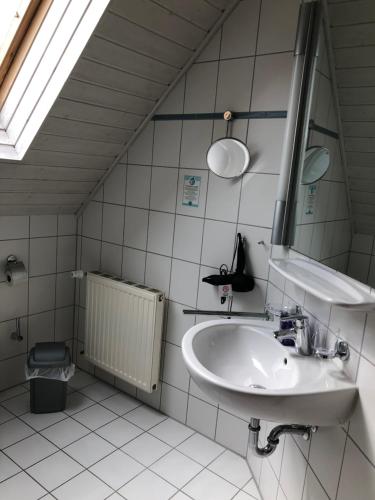 a white bathroom with a sink and a mirror at Ferienwohnung im Donautal in Altheim